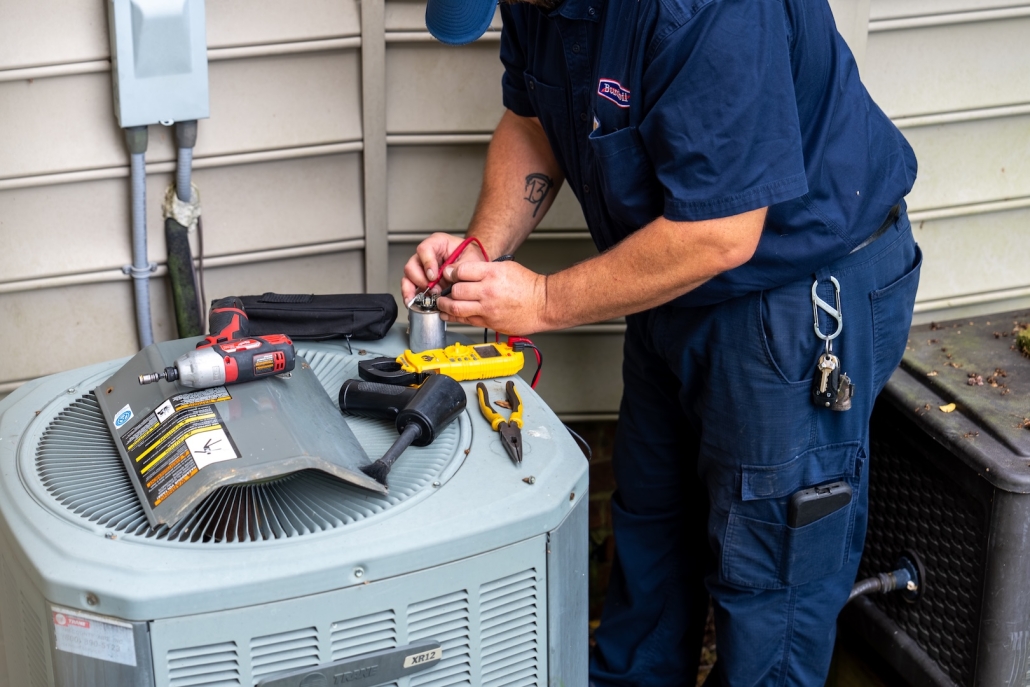 Burch technician working on an outdoor heating/air conditioning unit.