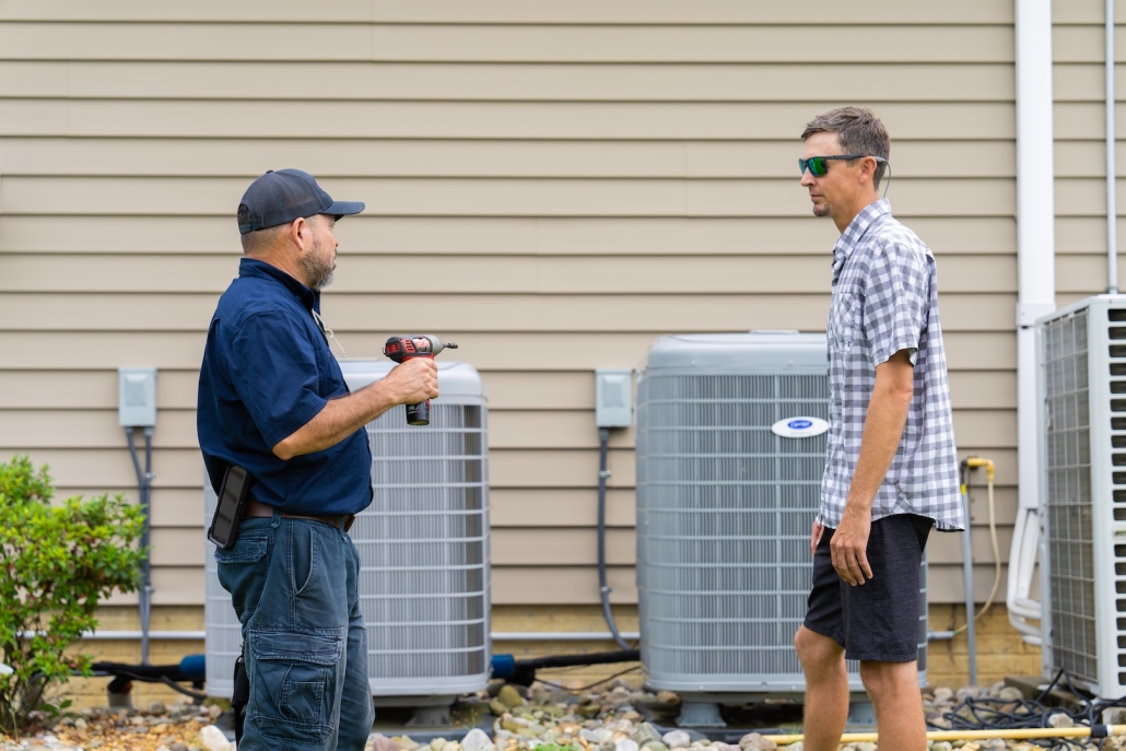 Burch technician working with a customer for their heating and cooling unit after doing an AC repair.