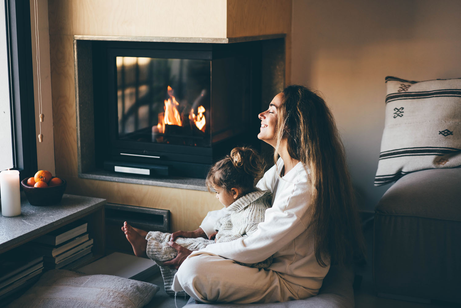 Woman sitting in front of a gas fireplace with her daughter in her lap.