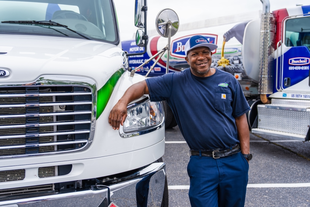 Burch worker smiling and leaning on truck