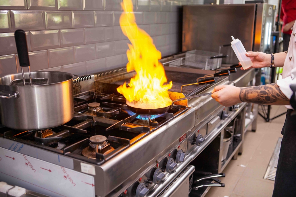 chef cooking on a propane gas stove in commercial kitchen