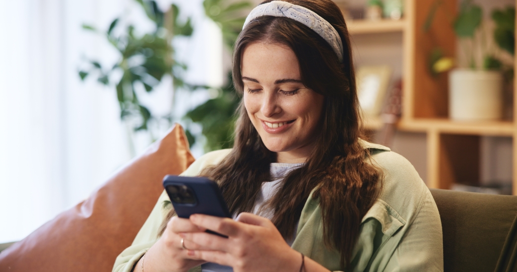 woman smiling at home looking at phone