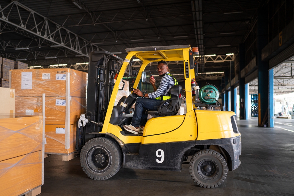 warehouse worker driving a forklift with a two-way radio
